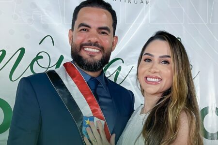 Paulo Curió e Eva Curió sorriem durante cerimônia de posse em Turilândia. Ele usa terno azul escuro e faixa de prefeito; ela veste roupa clara e tem cabelos castanhos com mechas loiras.
