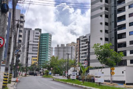 Avenida vista do nível da calçada, com edifícios residenciais altos dos dois lados e mais torres se estendendo até o fundo da via.
